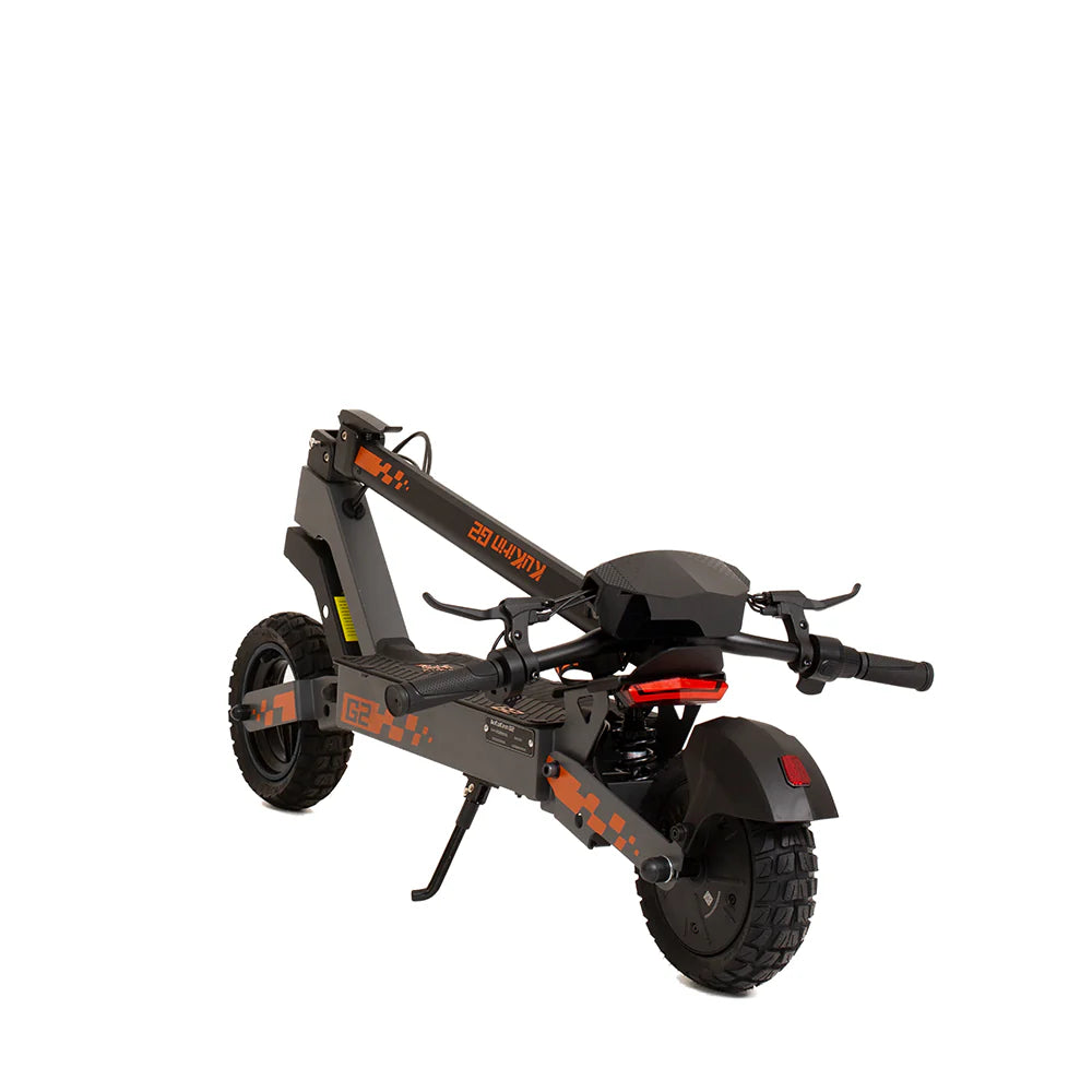 The folded KuKirin G2 800W električni romobil, in matte black with orange accents, features terenske vakuumske gume, rear suspension, and visible deck branding. Positioned against a white background, it offers snažne performanse for an exceptional ride.